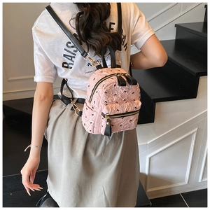 Detail eines rosa gesteppten Mini-Rucksacks mit schwarzen Schleifenmustern und Gurten