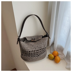 Detailed macro view of woven raffia shoulder bag with mesh knit pattern and toggle closure
