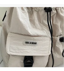 Detail der cremefarbenen Kordeltasche mit strukturiertem Nylon und schwarzem Verschluss