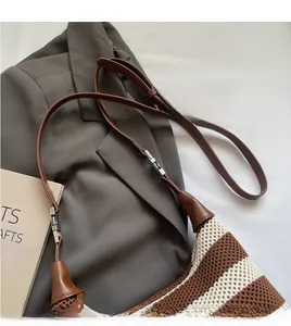 Detail of adjustable leather strap and silver buckle on striped woven shoulder bag