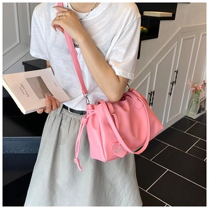 Detail of pink pleated bucket bag with drawstring closure and heart charm accessory