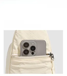 Détail de la poche zippée antivol au dos du sac à bandoulière en nylon blanc cassé