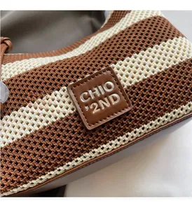 Close-up of knit texture and leather brand label on the brown and white striped handbag