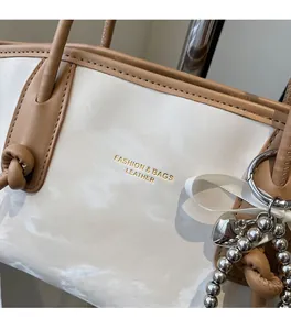 Dettaglio borsa shopper bianca effetto marmo con manici in pelle marrone e ciondolo argento