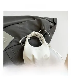 Detail view of the white ruched handle handbag with gold foil lettering on gray suit