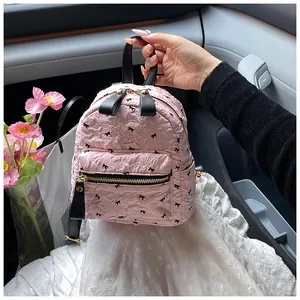 Detailansicht eines rosa gesteppten Mini-Rucksacks mit schwarzen Schleifen