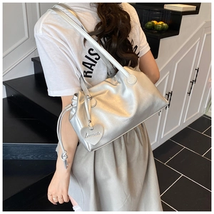 Silver shoulder bag with pleated texture and heart pendant shown on model