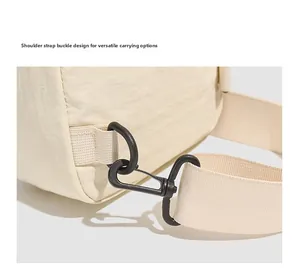 Détail du crochet métallique noir et de la bandoulière en nylon beige d'un sac à dos