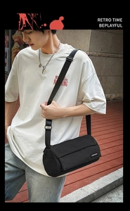 Gros plan d'un sac bandoulière cylindrique noir en toile avec une large sangle réglable