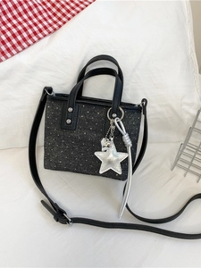 Black polka dot denim bucket bag with star pendant and sleek faux leather handles