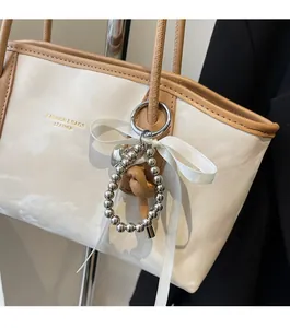 Dettaglio della borsa tote premium con texture marmo, manico marrone e ciondolo elegante
