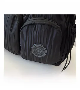 Close-up of black nylon backpack featuring vertical pleats and circular vintage logo badge