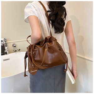Detail of dark brown leather bucket bag featuring a drawstring closure and heart charm