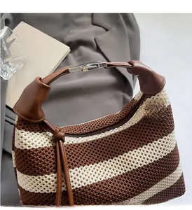 Detail of knit handbag with brown leather handle and fringe charm on a blazer