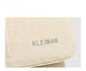 Gros plan d'un sac bandoulière beige en nylon avec fermeture éclair et logo Kleiman