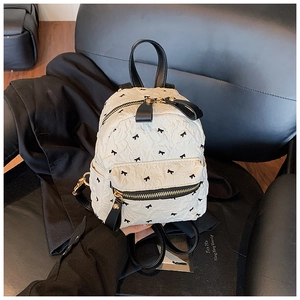 Detailaufnahme des plissierten Stoffes und der schwarzen Schleifenstickerei am Mini-Rucksack