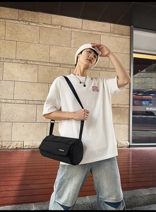 Photo street style d'un sac bandoulière cylindrique noir avec bandoulière réglable