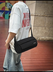 Détail du sac cylindrique noir avec bandoulière en tissu et étiquette de marque