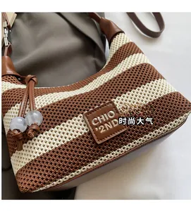 Detail of striped knit tote with leather logo tag and decorative white bead charm