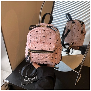 Detailansicht des rosa Rucksacks mit schwarzem Schleifendruck und goldener Hardware