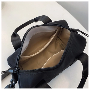 Vue de dessus montrant l'intérieur kaki spacieux et les poches zippées du sac en nylon noir