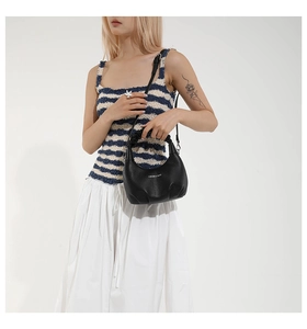 Vue détaillée du sac dumpling en cuir noir avec poignée froncée porté par un mannequin