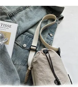 Détail du sac à cordon en nylon beige avec bandoulière réglable sur veste en denim