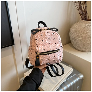 Detailaufnahme des rosa Knitterstoffs und der dekorativen schwarzen Schleifen am Rucksack