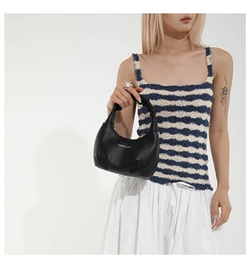 Détail d'un sac à main demi-lune en cuir noir grainé avec une poignée plissée chic