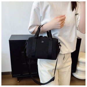 Détail du sac polochon en tissu noir avec doubles poignées et bandoulière réglable