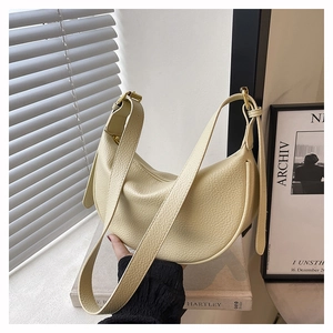 Detail der cremefarbenen Mondsichel-Tasche mit Lychee-Leder und goldener Hardware