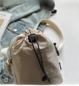 Détail du sac seau en nylon beige avec fermeture à cordon et détails de sangle tissée