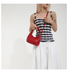 Détail d'un sac à main rouge en cuir avec poignée froncée et texture grainée