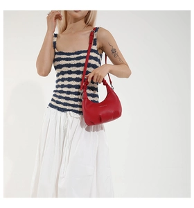 Détail du sac à bandoulière en cuir rouge avec base plissée et poignée froncée élégante