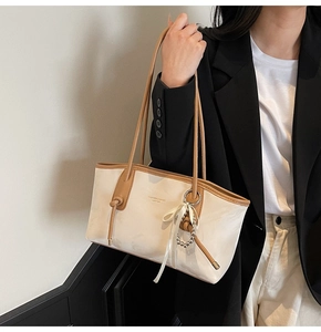 Dettaglio della borsa tote in ecopelle crema con manici color caramello e modella