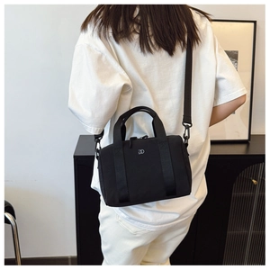 Détail du sac bandoulière en nylon noir avec logo DD argenté et large sangle