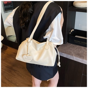 Close-up of cream white bucket bag with pleated texture and heart-shaped leather pendant