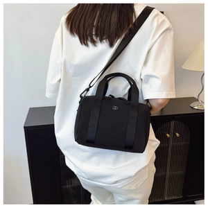 Sac bandoulière en nylon noir avec logo DD porté par un mannequin sur fond minimaliste