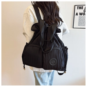 Detail of black pleated backpack showing drawstring closure and quilted nylon texture
