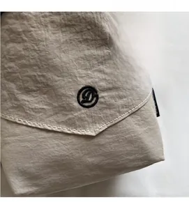 Détail du sac bandoulière en nylon imperméable kaki avec texture matelassée et broderie D