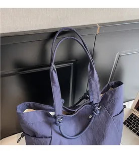 Detail of navy blue tote bag with knotted handles and side drawstring details on a desk