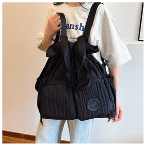 Detail of black nylon backpack with vertical pleats and large front zipper pockets