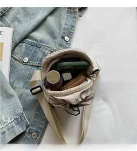 Vue de dessus du sac bandoulière en nylon beige montrant l'espace de rangement interne