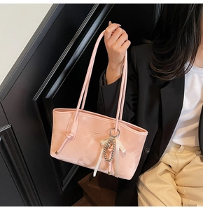 Dettaglio borsa tote in pelle PU rosa con nastro di seta e ciondolo a perline metalliche