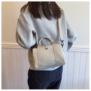 Gros plan d'un sac à bandoulière en toile beige porté par un mannequin en studio