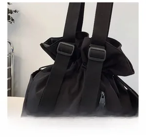 Close-up of adjustable fabric shoulder strap and side zipper pocket on a black travel bag