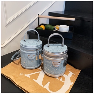 Détail d'un sac seau cylindrique avec strass étincelants et breloque cadenas en métal