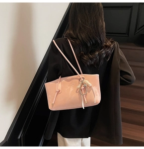 Borsa tote rosa in vernice con spalline sottili e ciondolo di perle indossata da modella