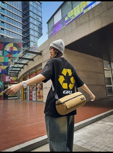Style urbain d'un sac bandoulière cylindrique kaki porté avec un t-shirt noir à graphique