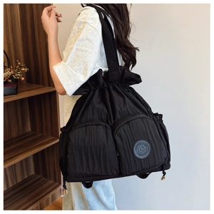 Detailed close-up of large black nylon backpack with drawstrings and two front zip pockets